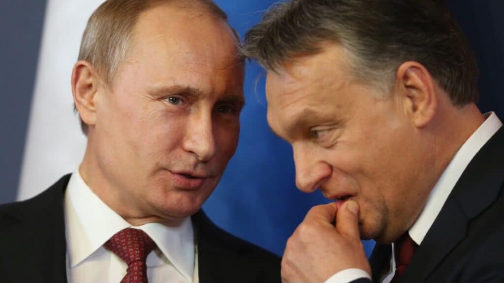 Két férfi beszélget, egyikük gondolkodva a kezét a szája elé teszi.