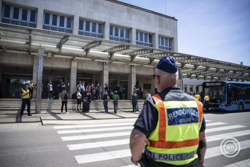 Felsővezetékes rendőri felügyelet az utasokkal teli buszállomás előtt.